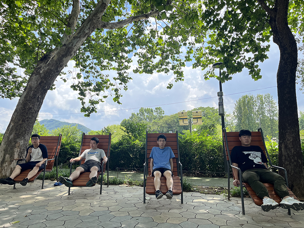 나무 밑 야외 벤치에 앉아 쉬고 있는 이용자들 사진